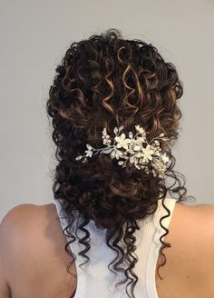 the back of a woman's head with curly hair and flowers in her hair