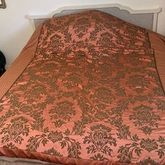 a bed with an orange and brown bedspread on it's headboard