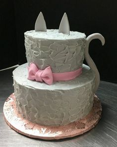 a three tiered cake with white frosting and pink bows