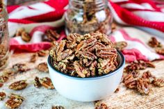 a bowl filled with pecans sitting on top of a table next to two glass jars