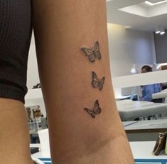 a woman's arm with three small butterflies on the back of her left arm