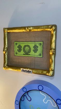 a dollar bill is on the wall next to a blue plate and gold rimmed bowl