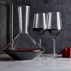 three wine glasses and a decanter are sitting on a counter with a red bow