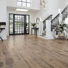 a large open floor plan with wood floors and white walls, black railings, and chandelier