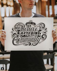 a man holding up a sign with the words we believe in fostering community on it