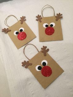 three brown paper bags with reindeer noses on them, one has glitter eyes and the other has