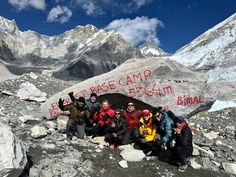 a group of people posing for a photo in front of some mountains with writing on them