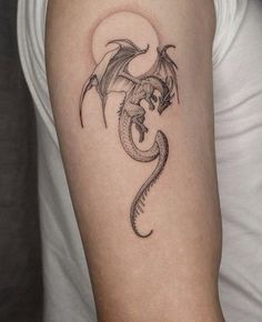 a woman's arm with a dragon tattoo on the left side of her arm