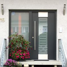 the front door is decorated with flowers and potted geranias on the steps