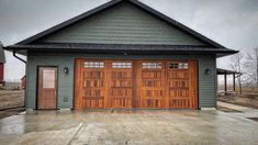 two brown garage doors in front of a gray house