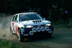 a white car driving down a dirt road