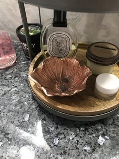 an assortment of skin care products on a wooden tray next to a candle and soap dispenser