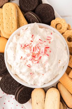 a white bowl filled with whipped cream surrounded by cookies