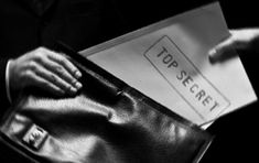 a black and white photo of someone's hand holding a top secret file folder