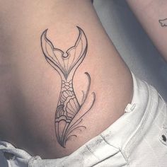 a woman's stomach with a fish tattoo on her lower back and side ribs