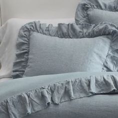 a bed with blue ruffled sheets and pillows