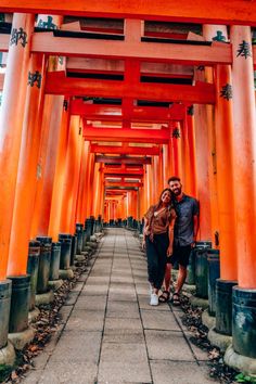 a man and woman are standing under an orange archway in the middle of a walkway