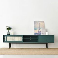 an entertainment center with a green cabinet and pictures on the wall behind it in a living room