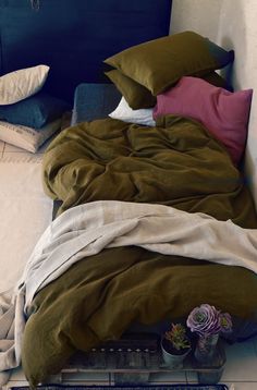 an unmade bed with several pillows and blankets on it