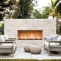 an outdoor fire place with two chairs and a couch in front of the fire pit