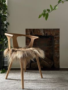 a chair with fur on it in front of a fire place and potted plant