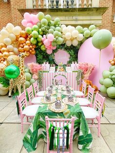 a table is set up for a party with balloons and jungle themed tablescapes