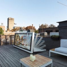 an outdoor living area with couches, table and television on top of the roof