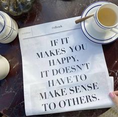 a newspaper with a cup of tea on it next to some cups and saucers