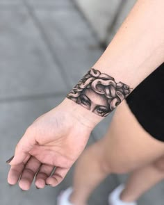 a woman's hand with a black and white tattoo design on the left wrist