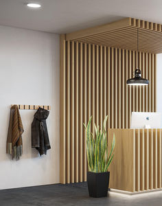 a plant in a black pot next to a wall with wooden slats on it