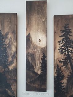 three wooden wall hangings with mountains and trees painted on them