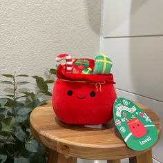 a small red bag sitting on top of a wooden stool next to a potted plant