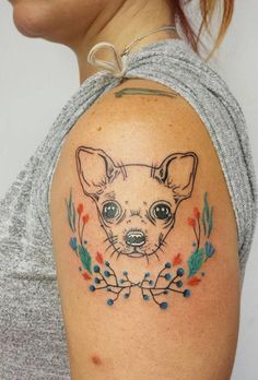 a woman's arm with a small chihuahua tattoo on the left side of her shoulder