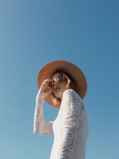 a woman wearing a hat and sunglasses looking up into the sky