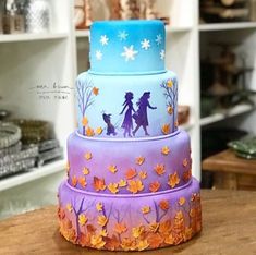 a three tiered cake decorated with frosting and fall leaves on a wooden table