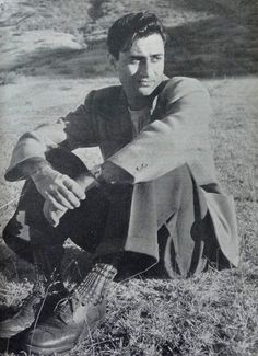 black and white photograph of a man sitting in the grass with his hand on his knee