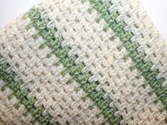 a crocheted dishcloth with green and white stripes on it, sitting on a table