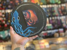 a person holding up a paper plate with an octopus on it in front of a store display