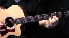 a man is holding an acoustic guitar in his hands and playing it with both hands