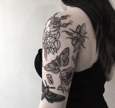 the back of a woman's arm with flowers and butterflies tattooed on her shoulder