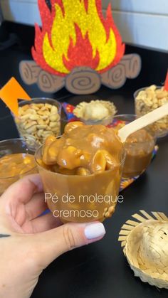 a hand holding a spoon over a bowl of food on top of a black table