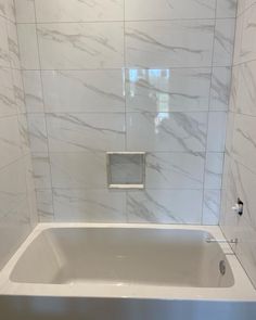 a white bath tub sitting inside of a bathroom next to a shower head mounted on the wall