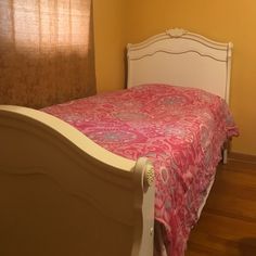 a bed with a pink bedspread sitting next to a window