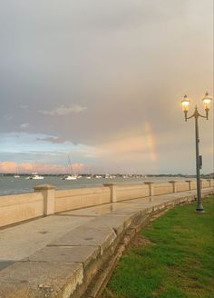 there is a rainbow in the sky over the water and some boats on the water