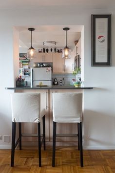 two white chairs sitting in front of a kitchen counter