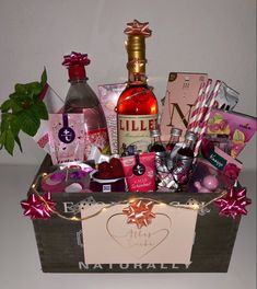 a wooden box filled with lots of different types of gifts and liquor bottles next to a plant