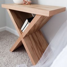 a white vase sitting on top of a wooden shelf next to a book case and bed