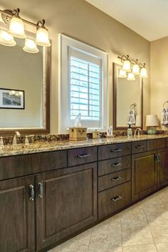 a large bathroom with double sinks, mirrors and lights on the wall above them is shown