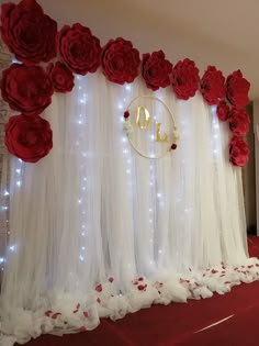 a room with red flowers and lights on the wall, decorated with white tulle