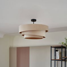 a living room with a round light fixture hanging from the ceiling and bookshelves